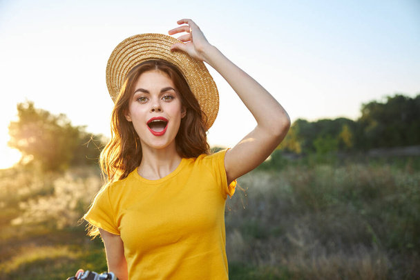 Vrolijke vrouw met open mond houdt hand op hoed natuur vakantie fotograaf - Foto, afbeelding