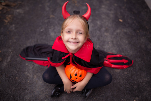 Little Girl in costume of devil with red horns outdoor. Happy Halloween concept. High quality photo - Photo, image