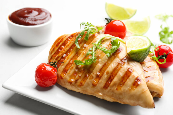 Tasty grilled chicken fillets with cherry tomatoes, lime slice and arugula on light table, closeup - Фото, зображення