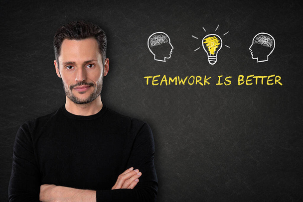 Young man with arms crossed, heads with heads, light bulb idea and text "Teamwork is better" on a blackboard background. - Photo, Image