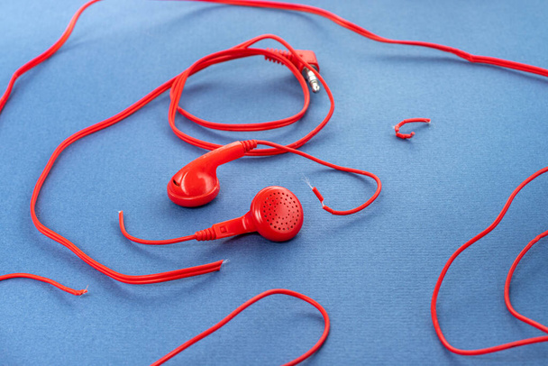 Headphones on a blue background. Torn headphones. Repair of electronic devices. Broken wire. - Фото, зображення