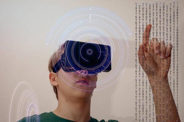 Hombre joven usando gafas de realidad virtual o auriculares que trabajan en la pantalla virtual con flujo de datos y hud - Foto, Imagen
