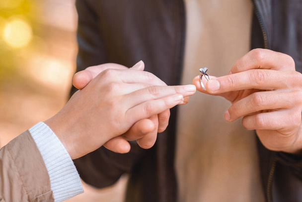 CLose up de hombre poniendo anillo en dedo femenino - Foto, Imagen