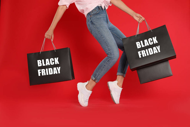 Woman with shopping bags on red background, closeup. Black Friday - Fotó, kép