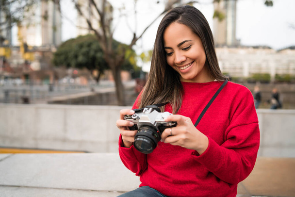 Portrait of young photographer woman using a professional digital camera outdoors. Photography concept - Fotó, kép