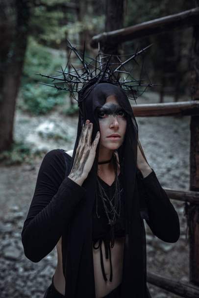 Misterioso feiticeira mulher bruxa belo vestido preto andar na floresta escura. senhora em olhar gótico. Roupa para halloween. - Foto, Imagem