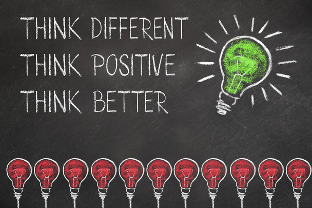 Light bulbs and writing "think different, positive & better" with an idea light bulb on chalkboard - Photo, image