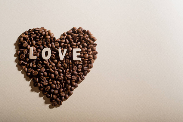 Coffee beans in the shape of a heart and the inscription love on a background - Zdjęcie, obraz