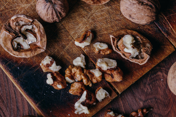 Walnut kernels and whole walnuts on rustic old wooden table. Top view. - Fotografie, Obrázek