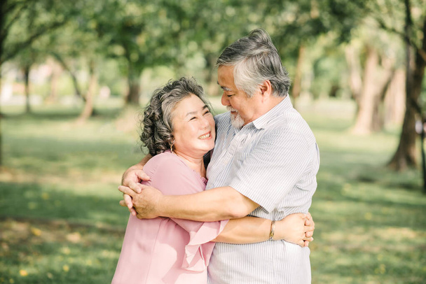 Happy senior Asian couple having a good time embracing and hugging outdoor in park - Photo, Image