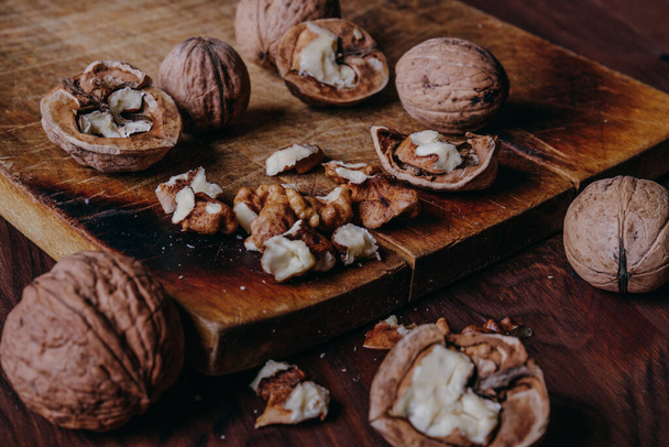 Walnut kernels and whole walnuts on rustic old wooden table. - Fotoğraf, Görsel