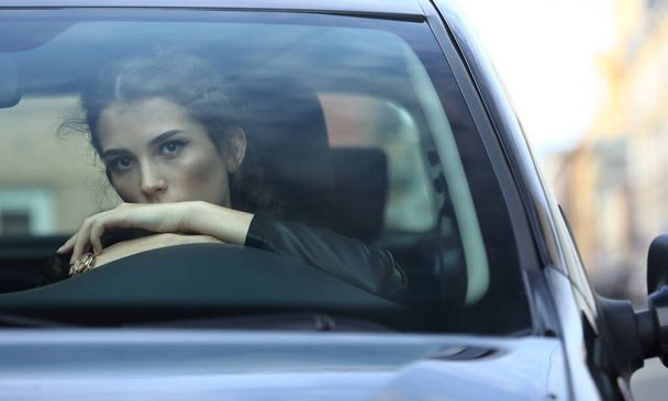Portrait of a beautiful girl behind the windshield of a car on the background of a city street - Valokuva, kuva