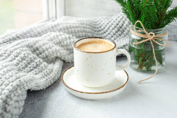 Cup of coffee, scarf and bouquet of fir tree branches. Cozy autumn or winter composition. Scandinavian style - Image - Фото, изображение
