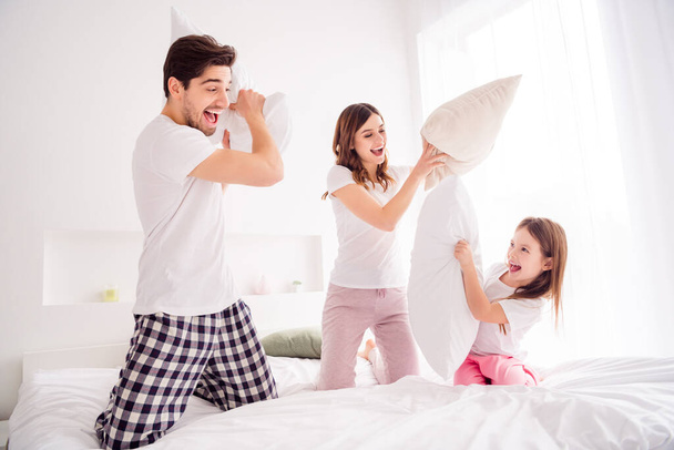 Photo of young family mommy daddy daughter sheets good mood spend together quarantine weekend playing games pillow fighting self isolation offspring bed bedroom indoors - Photo, Image