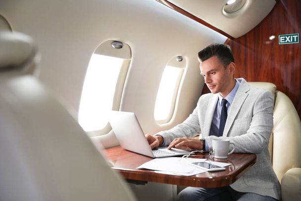 Young man working with laptop on plane. Comfortable flight - Foto, afbeelding