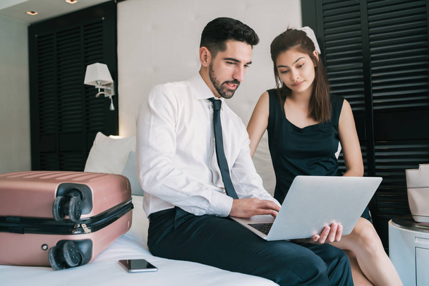 Portrait of two young business people working together on the laptop at the hotel room. Business travel concept. - Foto, imagen