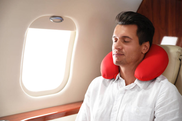 Handsome man with neck pillow sleeping during flight. Ait travel - Фото, изображение