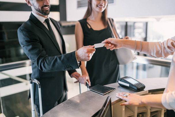 Close up of business people makes card payment at check-in at reception front desk. Business travel concept. - Foto, Imagem
