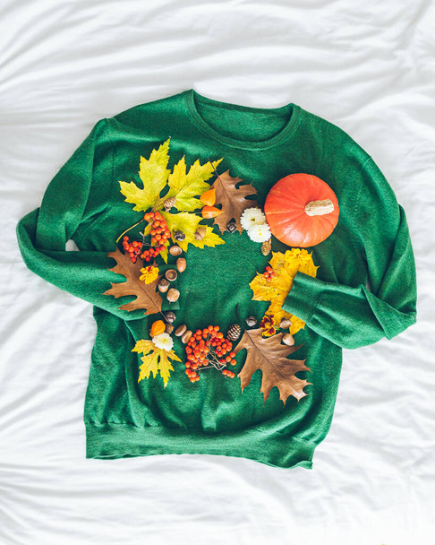 zöld pulóver őszi sárga levelekkel és narancssárga sütőtökkel. Üdvözlőlap. másolás helye - Fotó, kép