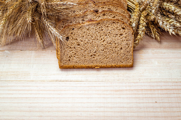 Ekmek kes. Buğday tohumu kulaklı bir somun taze ekmek ya da ahşap desenli bir bitki. Çavdar ekmeği ve ekmek kırıntılarıyla. Biyolojik malzemeler, çok sağlıklı tohumlar. - Fotoğraf, Görsel