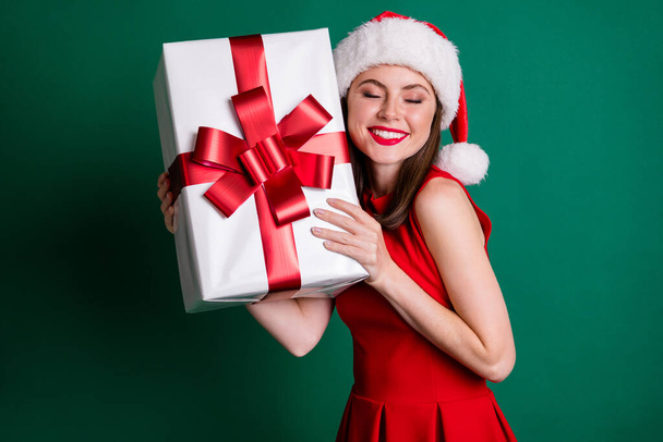 Photo positiivinen viehättävä tyttö joulupukki päähineet saavat x-mas uudenvuoden joulu yö toive lahjapaketti hän odottaa koko vuoden nauttia kulumista hame eristetty tummanvihreä väri tausta - Valokuva, kuva