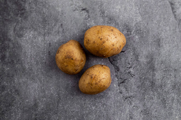 three potatoes on a gray background - Foto, Imagem