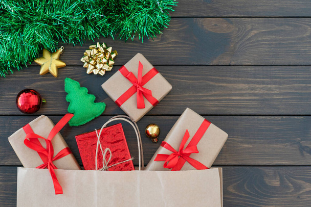 close up εικόνα των μικρών κουτιά δώρο κουρασμένος με κορδέλα, μπάλες του νέου έτους, πράσινο tinsel σε ξύλινο φόντο, copyspace για κείμενο. Ψώνια της Πρωτοχρονιάς. Χριστούγεννα και το νέο έτος έννοια - Φωτογραφία, εικόνα