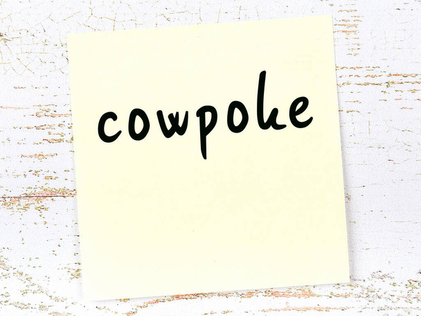 Yellow sheet of paper with word cowpoke. Reminder concept - Photo, Image