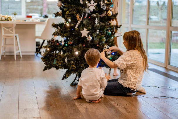 Children decorate the Christmas tree, brother and sister decorate the house for the holidays. Christmas holidays. Merry Christmas and Happy New Year concept. - Photo, Image