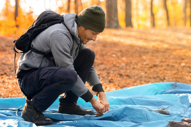 Молодой человек турист установка палатки, кемпинг в золотом лесу - Фото, изображение