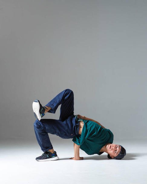 Cool b-boy dancing in studio isolated on gray background with copy space. Dancing school poster - Φωτογραφία, εικόνα