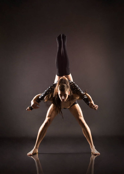 A young girl and young man performing acrobatic dance and stunts.Studio shooting on a dark background. - Φωτογραφία, εικόνα