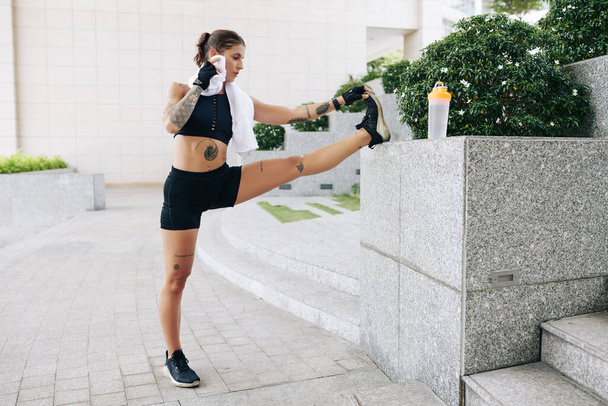 Підійде молода жінка, що витирає піт з чола при розтягуванні ніг після бігу вранці
 - Фото, зображення
