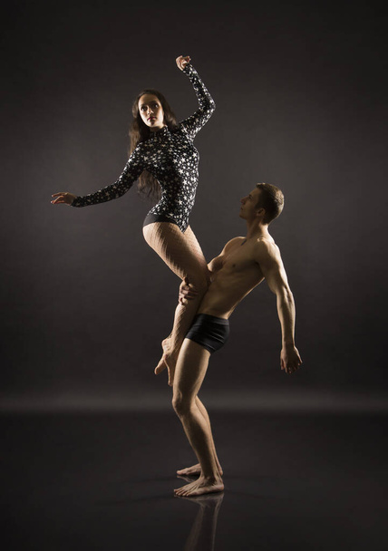 A young girl and young man performing acrobatic dance and stunts.Studio shooting on a dark background. - Фото, зображення