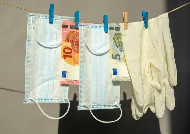 latex gloves and a medical face mask hang, euro banknotes money on clothespins hard light gray background . spending safety concept during covid coronavirus pandemic. - Fotografie, Obrázek
