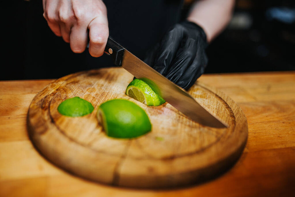 Slicing lime in black latex gloves - bartender job making cocktail - Fotó, kép