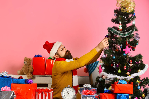 Santa decorates Christmas tree. Man with beard and concentrated face - Fotoğraf, Görsel