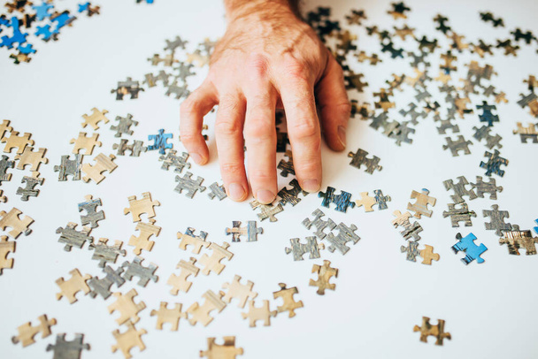 A man hand goes through the elements of the puzzle in search of a solution to the puzzle - find a way out of a difficult situation - many solutions - 写真・画像