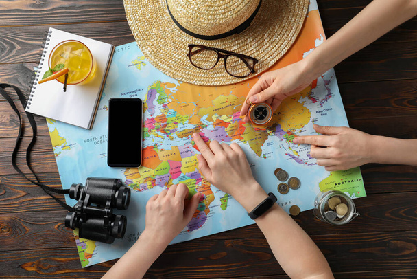 People with world map and accessories at table, top view. Travel during summer vacation - 写真・画像