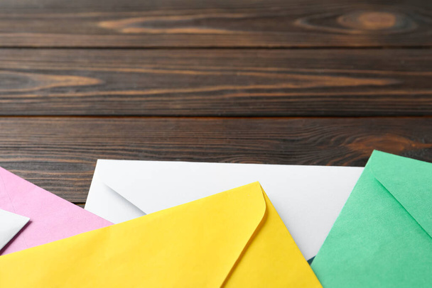 Colorful paper envelopes on wooden background, closeup. Space for text - Φωτογραφία, εικόνα