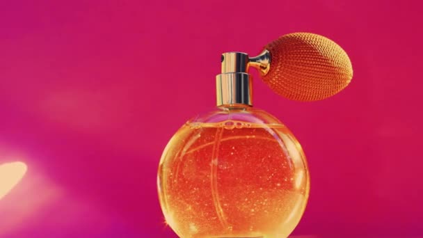 Złota butelka zapachowa i błyszczące flary na różowym tle, efektowny zapach perfum jako wakacyjny produkt perfumeryjny dla marki kosmetycznej i kosmetycznej - Materiał filmowy, wideo