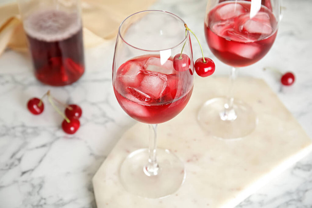 Delicious cherry wine with ripe juicy berries on white marble table - 写真・画像