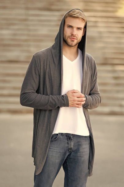 Comfortable clothes daily wear. Great taste to dress well. Male fashion influencer. Fashionable young model man. Street style outfit. Handsome man with hood standing urban background. Fashion trend - Zdjęcie, obraz