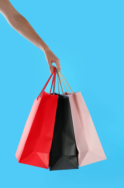 Woman with paper shopping bags on light blue background, closeup - Foto, Imagem