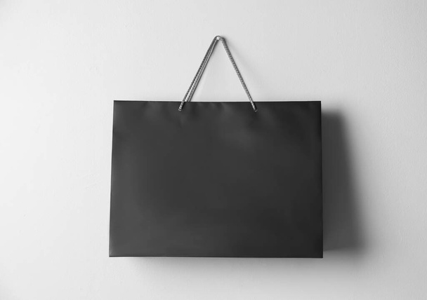 Paper shopping bag hanging on white wall - Φωτογραφία, εικόνα
