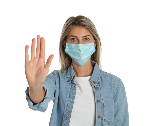 Woman in protective mask showing stop gesture on white background. Prevent spreading of coronavirus - Foto, Imagem