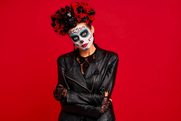 Sugar skull pretty girl with halloween makeup standing on bright red background. Wonderful female zombie with flowers in hair celebrating day of the dead - Φωτογραφία, εικόνα