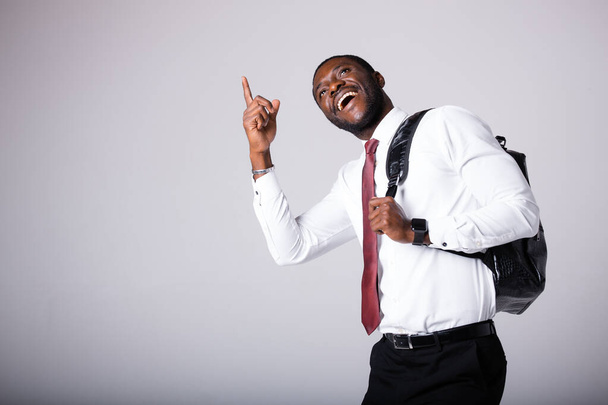 An African American man in a shirt and tie stands against a gray background,points his finger to the top and smiles.Space for text - Photo, image
