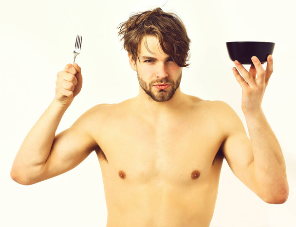 Caucasian sexy young macho holding black bowl with fork - Fotó, kép