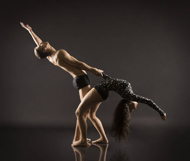 A young girl and young man performing acrobatic dance and stunts.Studio shooting on a dark background. - Valokuva, kuva